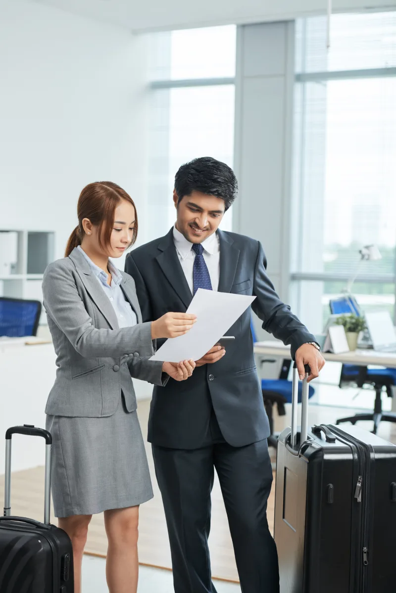 man-woman-business-suits-standing-office-with-suitcases-looking-together-document
